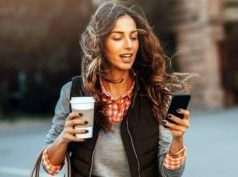 Image of a busy woman walking whilst holding a coffee in one hand and smartphone in the other.